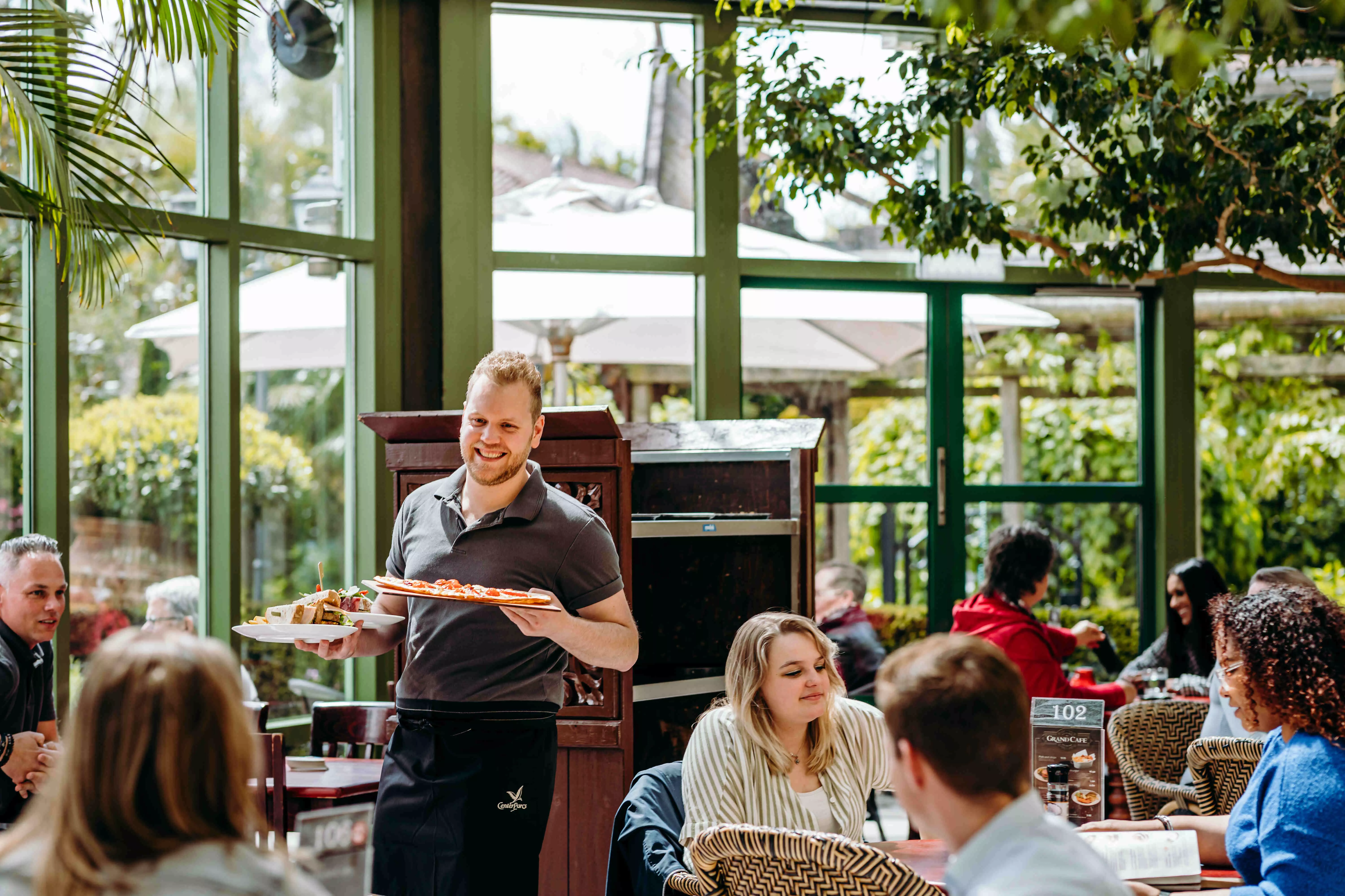 Medewerker bediening bij Albron serveert met een glimlach aan tevreden gasten