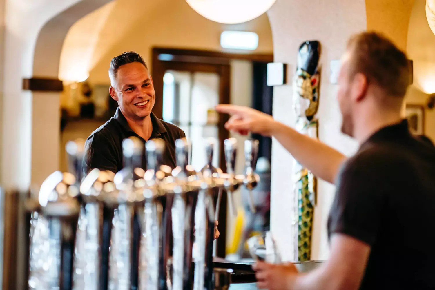 Medewerker bediening bij Albron serveert met een glimlach aan tevreden gasten