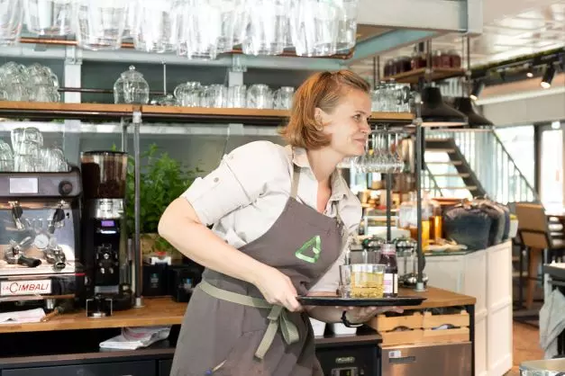 Medewerker bediening bij Albron serveert met een glimlach aan tevreden gasten 